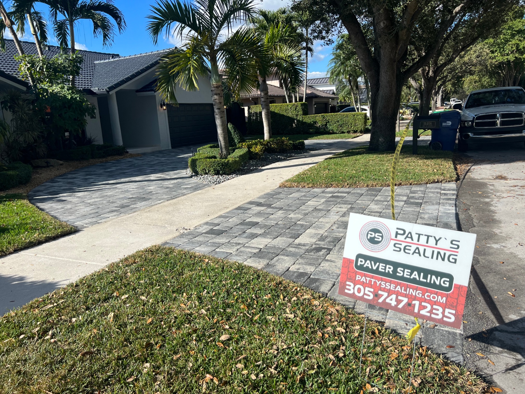 Freshly sealed brick paver driveway in South Florida with Patty's Sealing yard sign