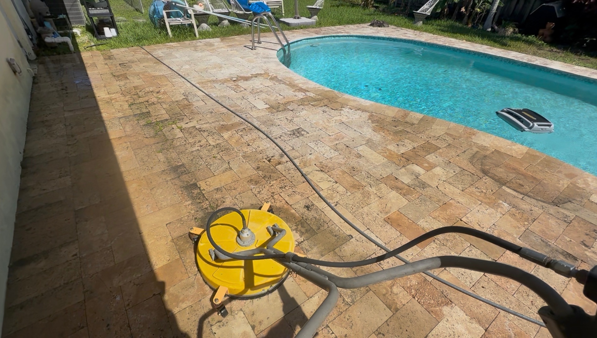 Surface cleaner pressure washing a travertine pool deck — dirty side vs. cleaned side visible